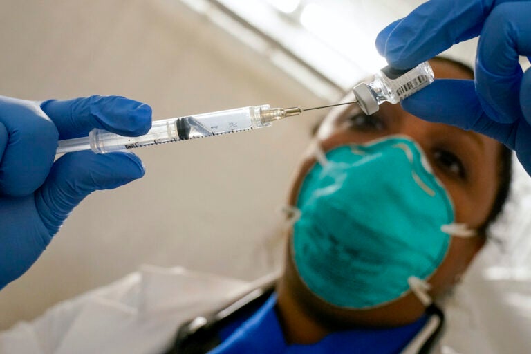 A doctor extracts COVID-19 vaccine out of a vial