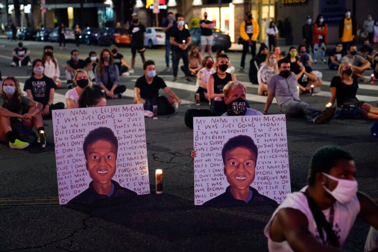 In this Aug. 24, 2020, file photo, two people hold posters showing images depicting Elijah McClain during a candlelight vigil for McClain outside the Laugh Factory in Los Angeles. (AP Photo/Jae C. Hong, File)