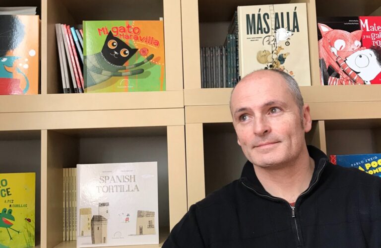 Enrique Morás stands in front of a bookshelf