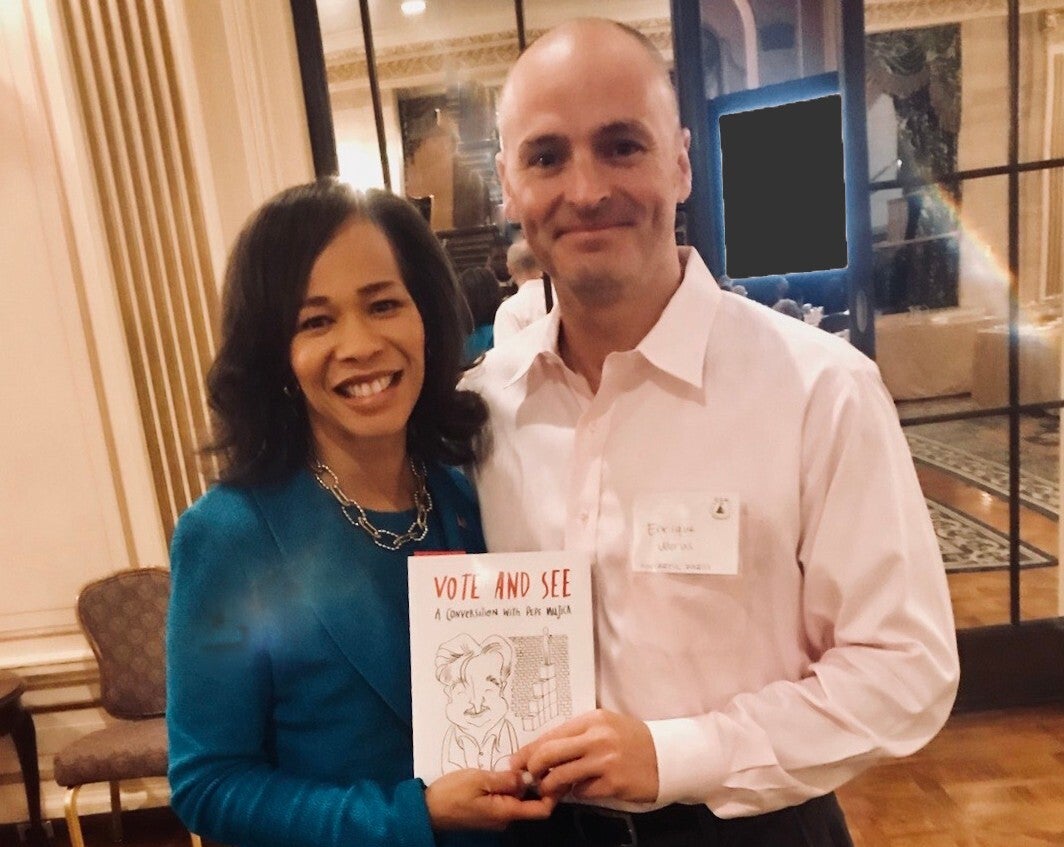 Syncretic Press founder Enrique Morás stands with U.S. Rep. Lisa Blunt Rochester, holding a copy of "Vote and See"