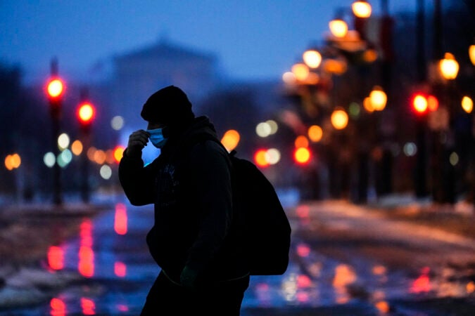 A person wearing a face mask as a precaution against the coronavirus walks during a winter storm in Philadelphia