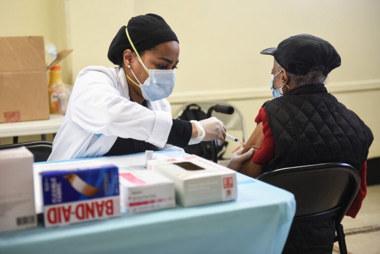 A person administers a COVID-19 vaccine