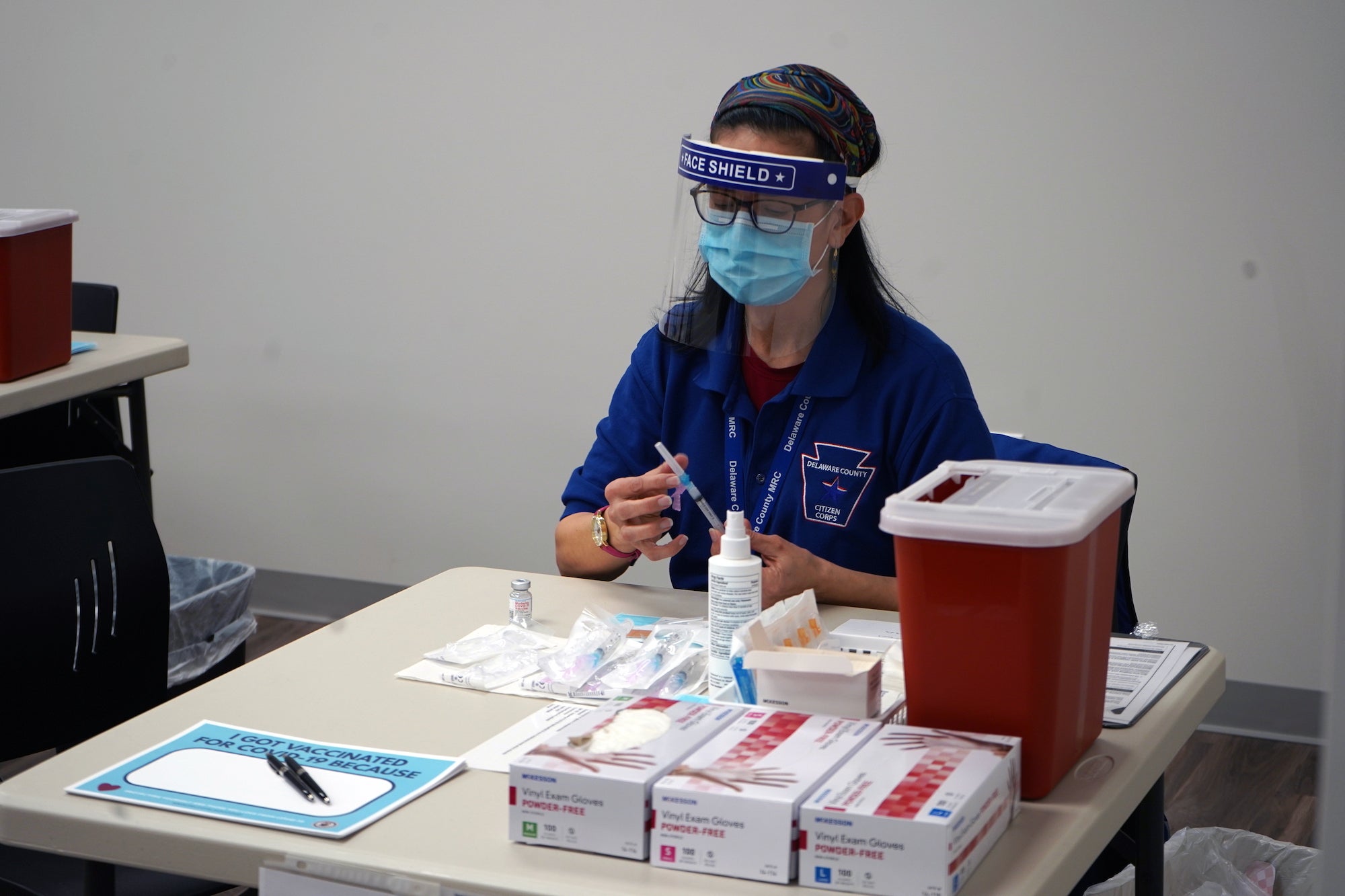 A worker wearing a face shield sits at a table at Delco's wellness center