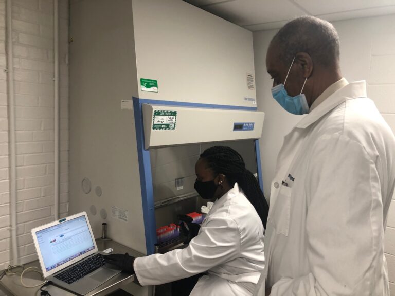 Audrey Janga works with COVID-19 test samples as medical director Dr. Harris Curtis observes. (Cris Barrish/WHYY)