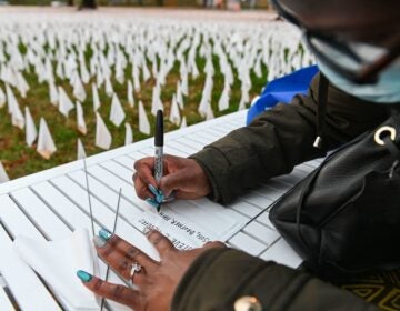 Patrice Howard writes on white flags before planting them to remember her recently deceased father and close friends