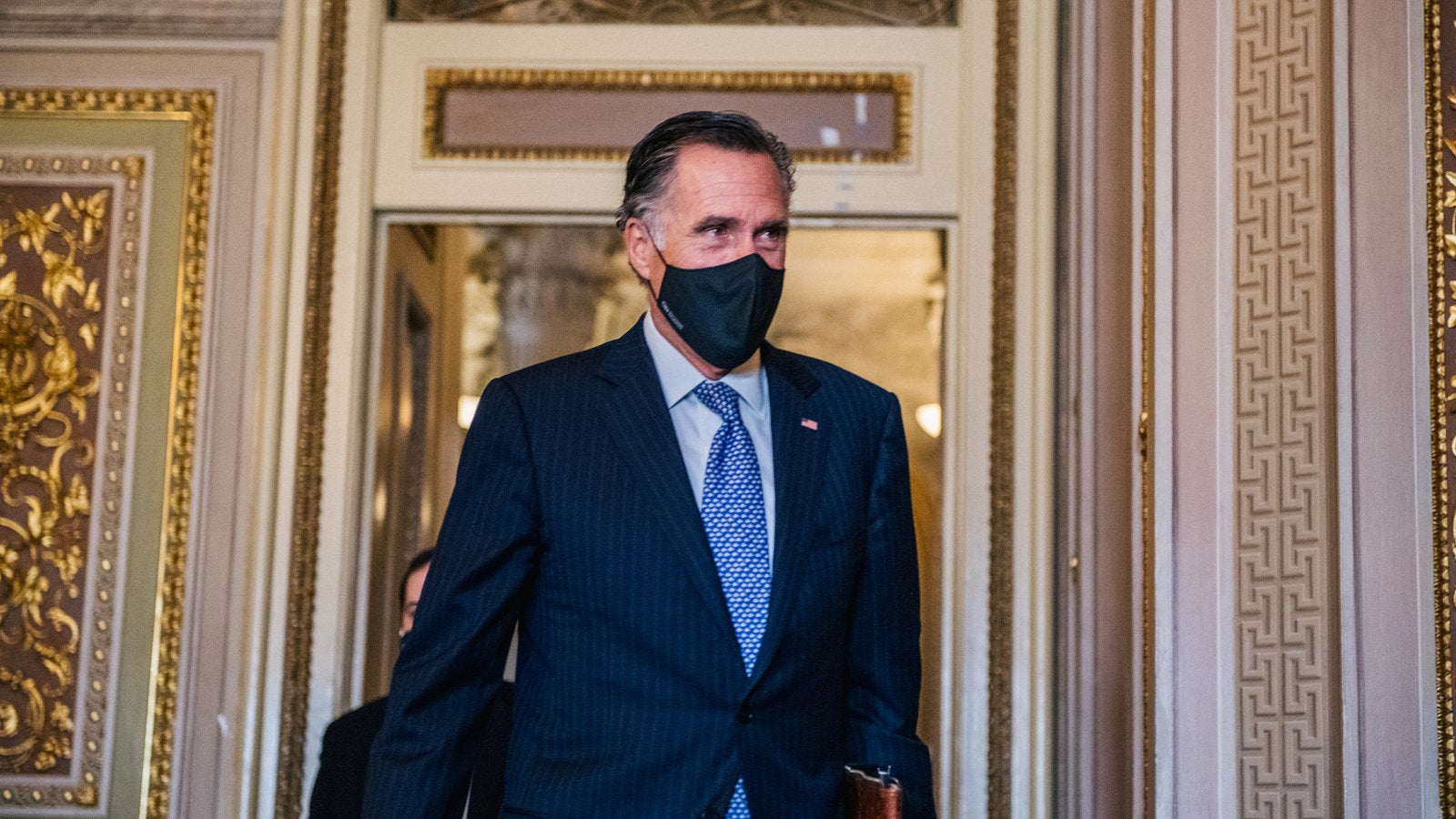 Sen. Mitt Romney wearing a face mask walking through the Capitol
