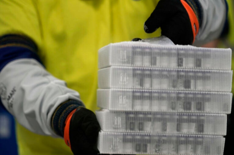 A worker carries boxes containing the Pfizer-BioNTech COVID-19 vaccine that were being prepared for shipment from a Pfizer facility in Portage, Mich., in December. (Morry Gash/Pool/Getty Images)