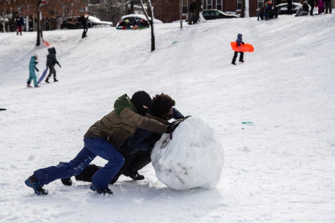 Kids roll a giant snowball at Clark Park