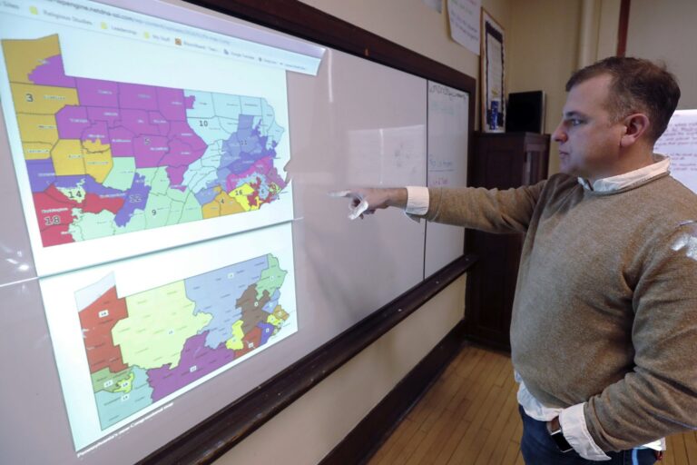 William Marx, points to projected images of the old congressional districts of Pennsylvania on top, and the new re-drawn districts on the bottom, while standing in the classroom where he teaches civics in Pittsburgh on Friday, Nov. 16, 2018. (Keith Srakocic/AP Photo)