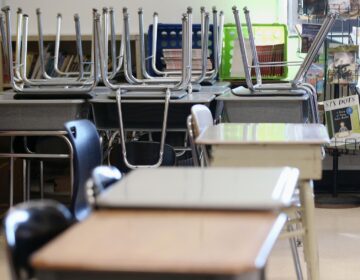 Desks are pictured in an empty classroom.