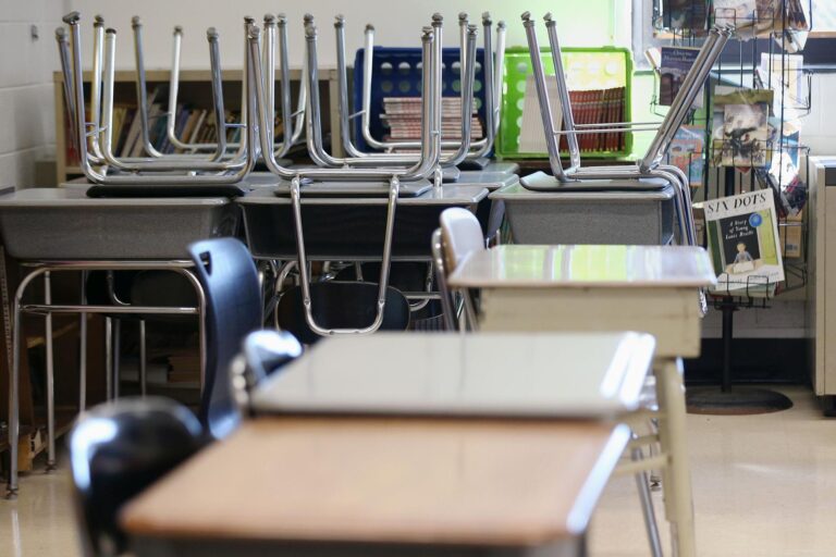 Desks are pictured in an empty classroom.