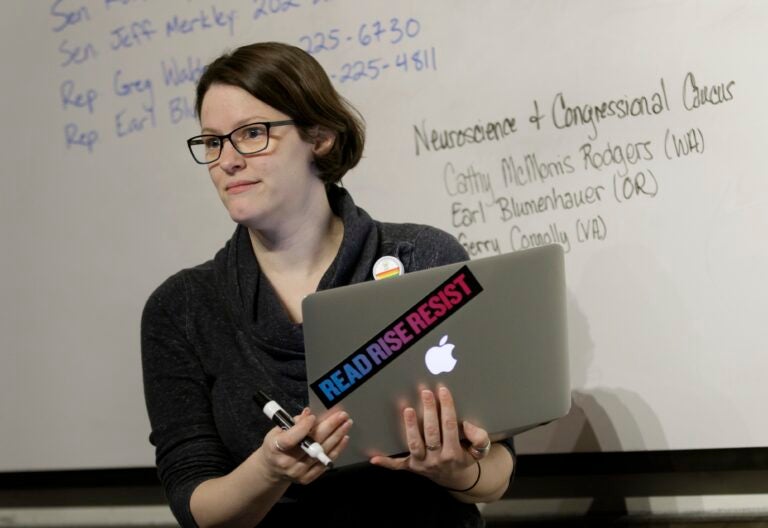 OHSU School of Medicine student Mollie Marr stands in front of a whiteboard holding a laptop. She helps organize a letter-writing campaign for students to share personal stories about the impact of losing a proposed tax waiver for tuition for graduate students, December 1, 2017. Marr is pursuing her M.D. and her Ph.D. in behavioral neuroscience in the OHSU School of Medicine, and losing the tax waiver could mean dropping out of OHSU. (OHSU/Kristyna Wentz-Graff)