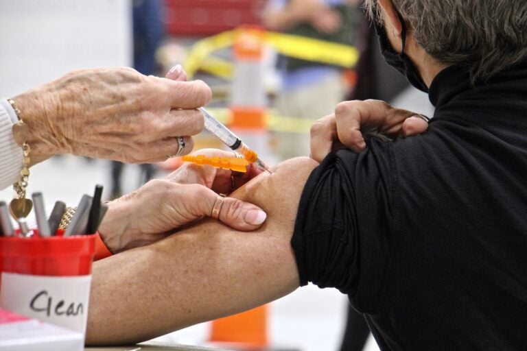 A person receives a COVID-19 vaccine at a community clinic