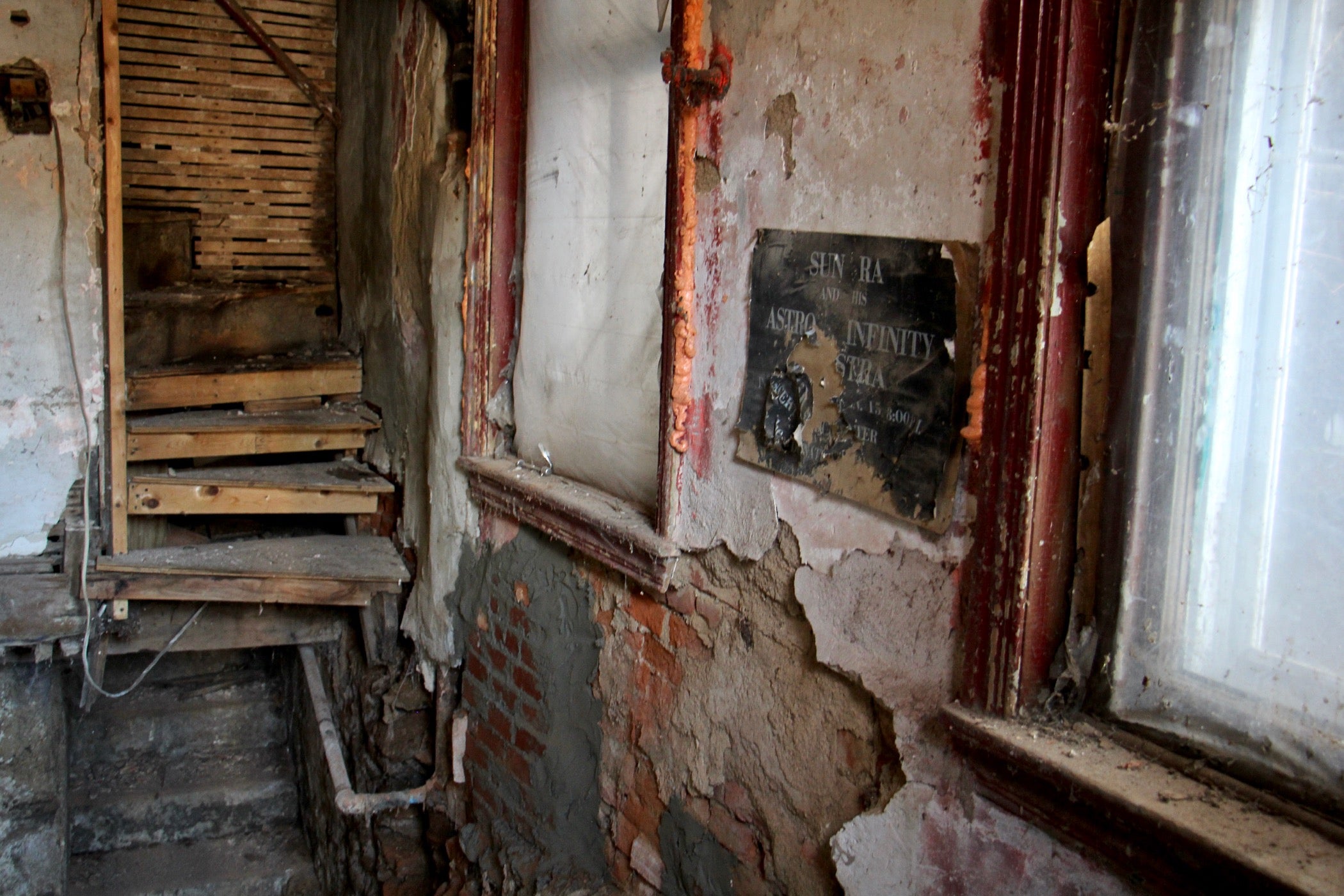 A Sun Ra poster remains affixed to the wall above the space where the floor collapsed into the sub-basement at the Sun Ra House