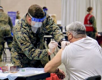 A National Guard member vaccinates someone against COVID-19 at the Pennsylvania Convention Center