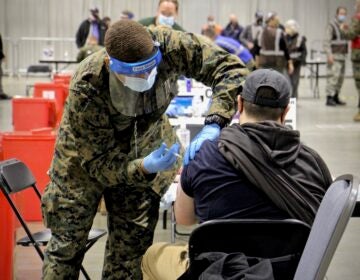 A National Guard member vaccinates someone against COVID-19 at the Pennsylvania Convention Center