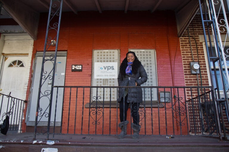 Racqueal Howard on the porch of the property she won in the Philadelphia Housing Authority-Jumpstart lottery in the Mantua section of West Philadelphia. She plans to renovate the home and sell it to a family. (Kimberly Paynter/WHYY)