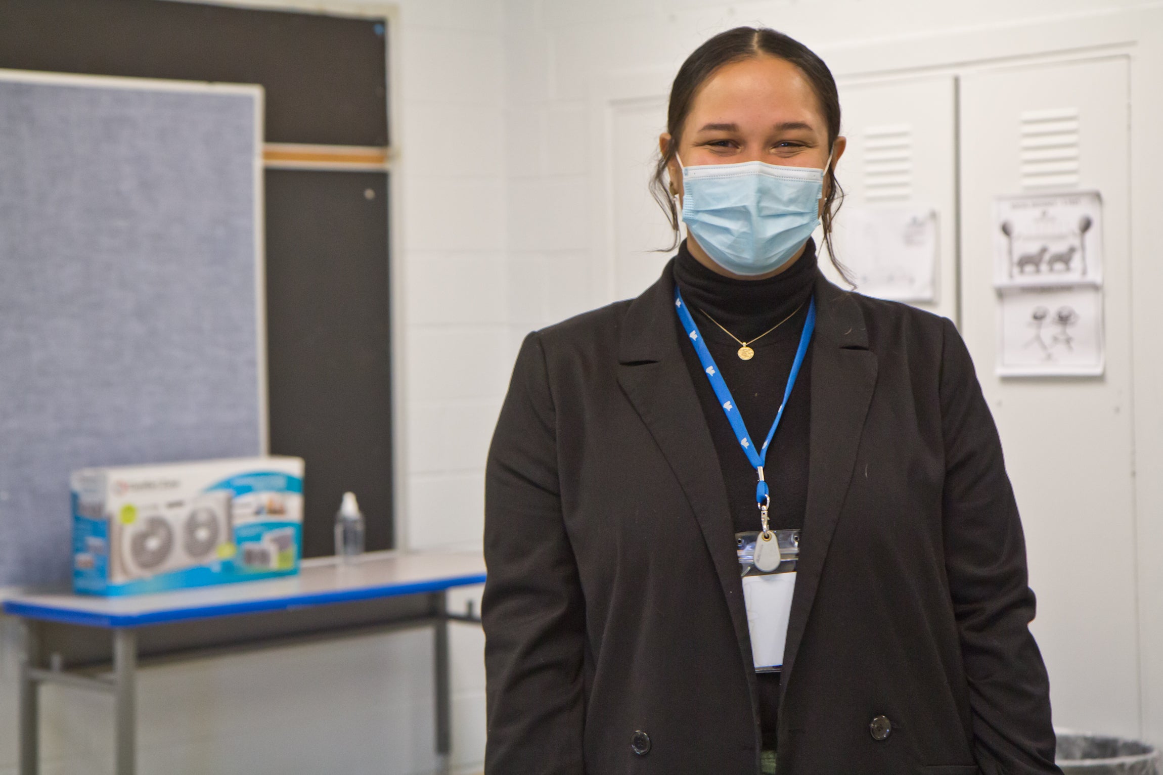 Alicia Bunch, wearing a face mask, stands inside a classroom