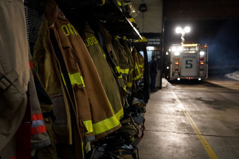 Firefighter coats are lined up, with an ambulance in the background