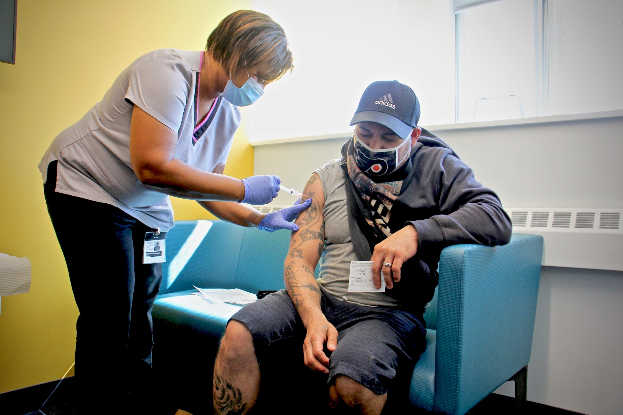 Licensed practical nurse Toni Dixon administers a COVID-19 shot to Angel Santiago