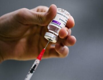 A pharmacist prepares a syringe from a vial of the AstraZeneca coronavirus vaccine during