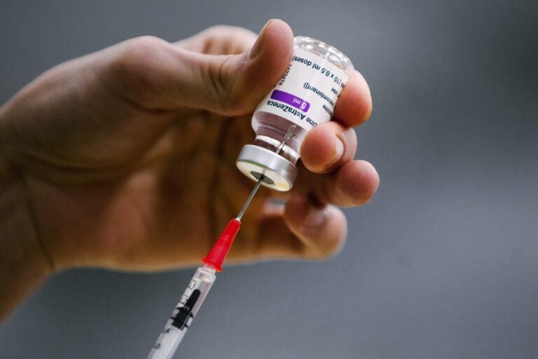 A pharmacist prepares a syringe from a vial of the AstraZeneca coronavirus vaccine during