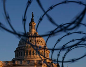 The Capitol is seen through razor wire at sunrise in Washington