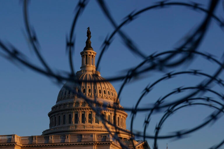 The Capitol is seen through razor wire at sunrise in Washington