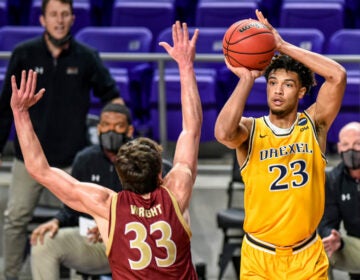 Drexel forward T.J. Bickerstaff (23) shoots over Elon forward Simon Wright (33) during the first half of an NCAA college basketball game for the Colonial Athletic Association men's tournament championship in Harrisonburg, Va., Tuesday, March 9, 2021. (AP Photo/Daniel Lin)