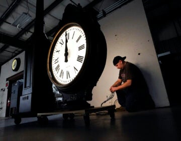 Electric Time technician Dan LaMoore lights up a two-dial Howard Post Clock, Tuesday, March 9, 2021, in Medfield, Mass. Daylight saving time begins at 2 a.m. local time Sunday, March 14, 2021, when clocks are set ahead one hour. (AP Photo/Elise Amendola)