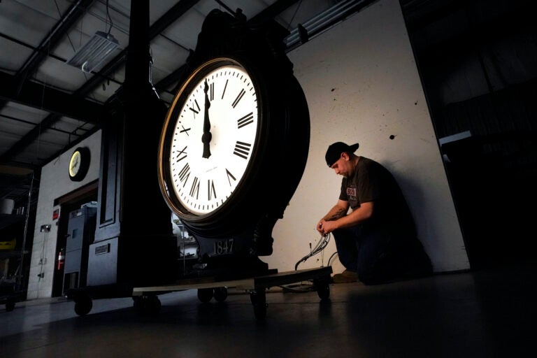 Electric Time technician Dan LaMoore lights up a two-dial Howard Post Clock, Tuesday, March 9, 2021, in Medfield, Mass. Daylight saving time begins at 2 a.m. local time Sunday, March 14, 2021, when clocks are set ahead one hour. (AP Photo/Elise Amendola)