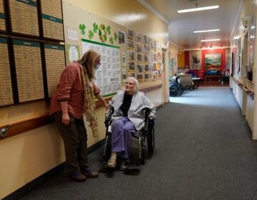 Chaparral House activities director Erika Shaver-Nelson, left, talks with resident Joyce in the hallway at Chaparral House in Berkeley, Calif., Thursday, March 18, 2021. (AP Photo/Jeff Chiu)