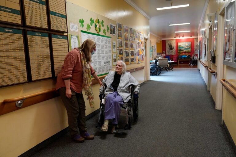 Chaparral House activities director Erika Shaver-Nelson, left, talks with resident Joyce in the hallway at Chaparral House in Berkeley, Calif., Thursday, March 18, 2021. (AP Photo/Jeff Chiu)