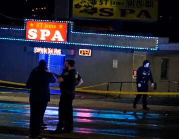 Officials stand in front of a massage parlor after a shooting