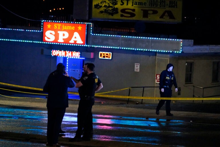 Officials stand in front of a massage parlor after a shooting