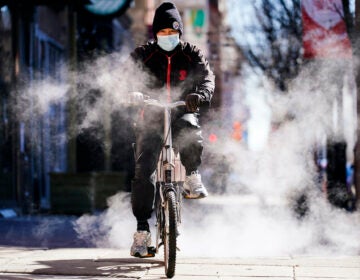 A person wearing a face mask as a precaution against the coronavirus rides a bicycle in Philadelphia