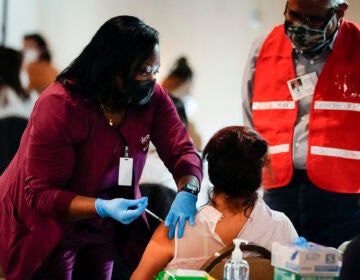 A health worker administers a dose of a Pfizer COVID-19 vaccine