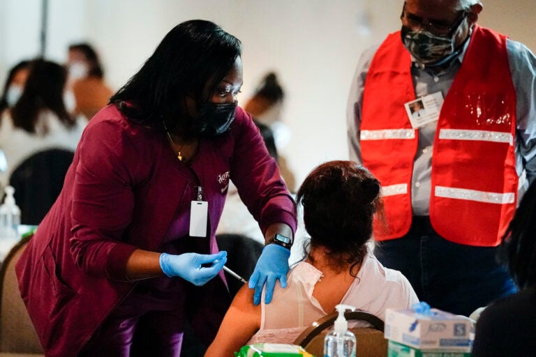 A health worker administers a dose of a Pfizer COVID-19 vaccine