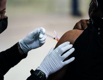 A member of the Philadelphia Fire Department administers the Johnson & Johnson COVID-19 vaccine to a person at a vaccination site setup