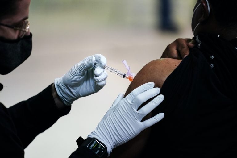 A member of the Philadelphia Fire Department administers the Johnson & Johnson COVID-19 vaccine to a person at a vaccination site setup