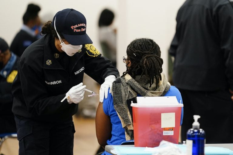 A member of the Philadelphia Fire Department administers a COVID-19 vaccine at a vaccination site