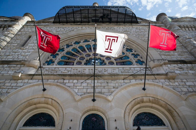 Flags wave in the wind from a building on Temple University's campus