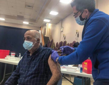 Joseph Dymowski, co-owner of Centennial Pharmacy, vaccinates Costa Monsour, a parishioner at St. Maron Maronite Catholic Church. (Nina Feldman / WHYY)