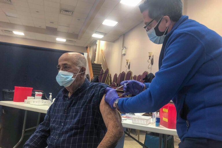 Joseph Dymowski, co-owner of Centennial Pharmacy, vaccinates Costa Monsour, a parishioner at St. Maron Maronite Catholic Church. (Nina Feldman / WHYY)