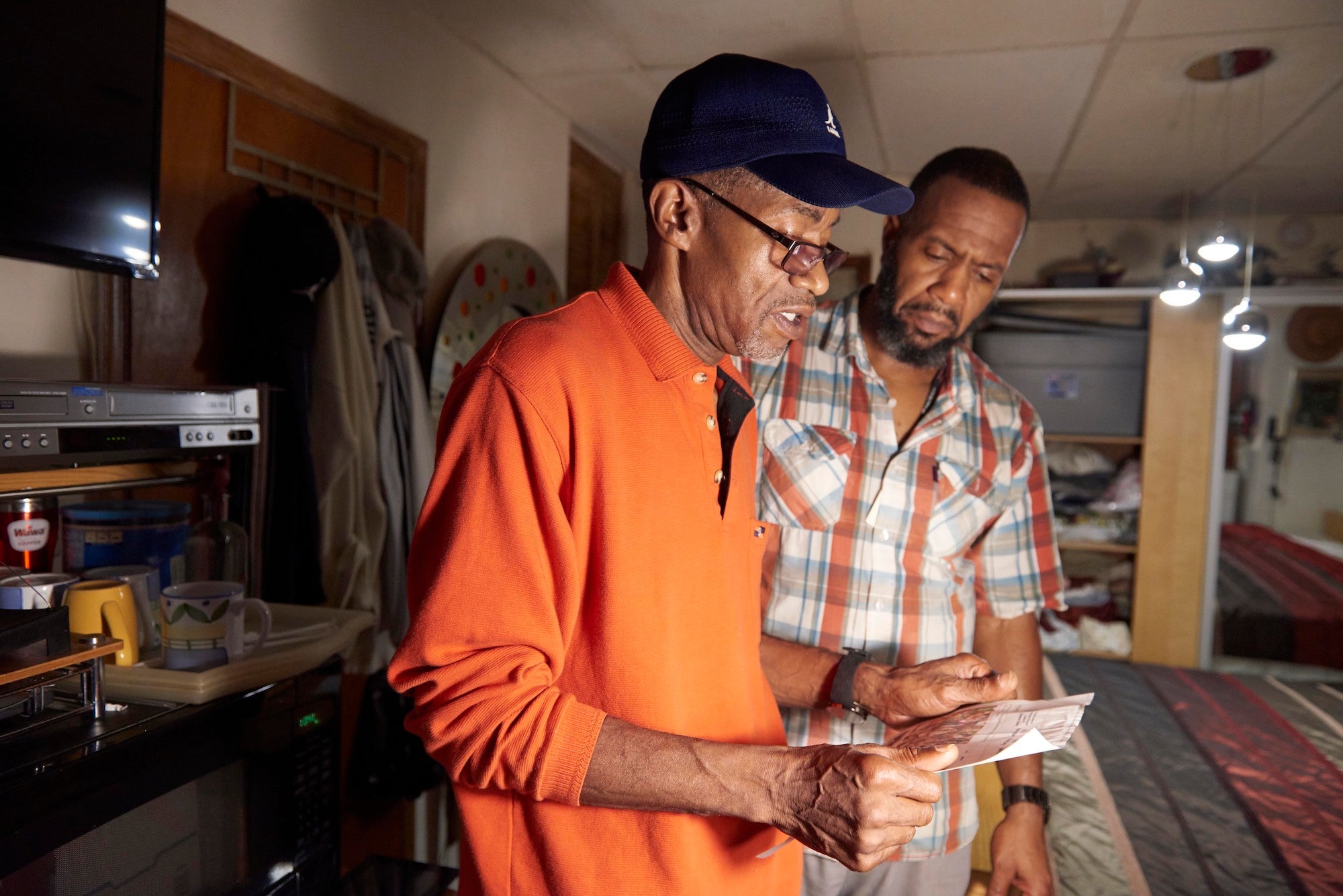 Walter Briggs (right) shows community health worker Orson Brown (left) a high utility bill during a home visit