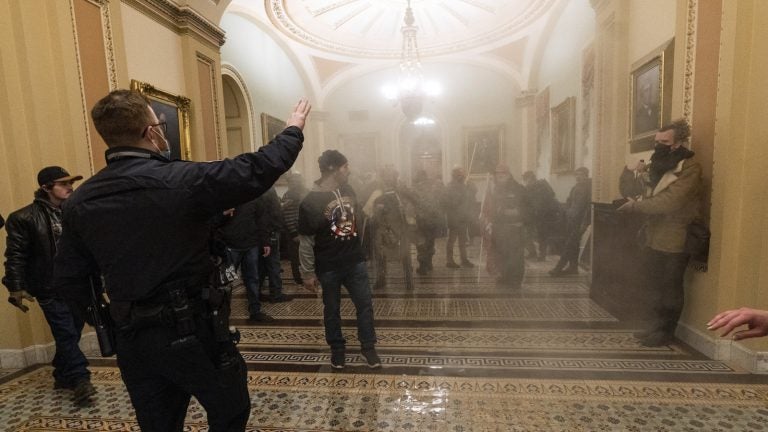 Smoke fills the walkway outside the Senate Chamber as rioters are confronted by U.S. Capitol Police officers inside the Capitol