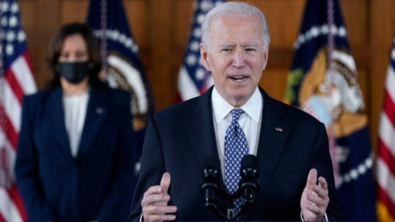 President Biden speaks while Vice President Harris is seen in the background.