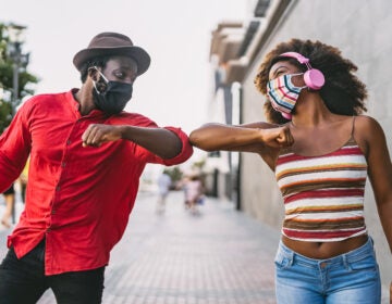 Two friends greeting each other with elbow bumps during the COVID-19 pandemic