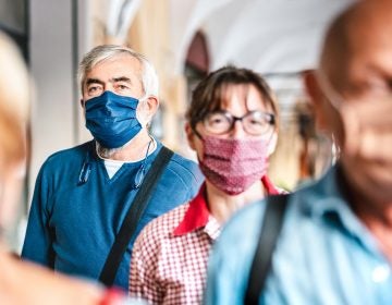 Crowd of adult citizens walking on city street wearing face masks