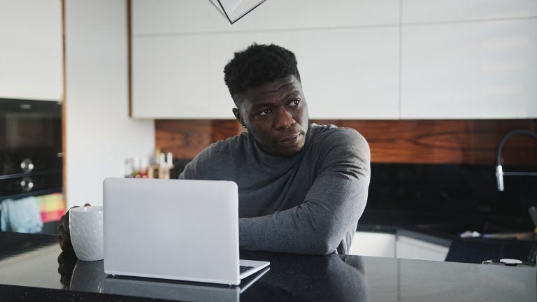 A young Black man working on laptop in his apartment